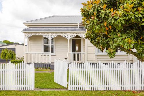 a white picket fence in front of a white house at Bryce Cottage in Cambridge