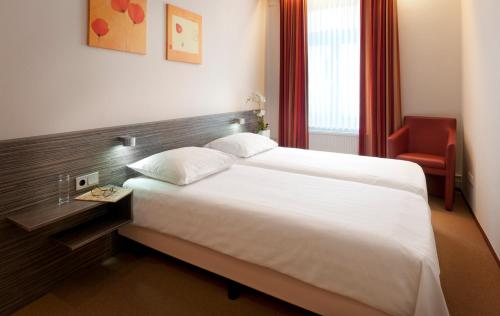 Cette chambre d'hôtel comprend un grand lit et un fauteuil rouge. dans l'établissement Appartementen Hotel Geuldal, à Epen