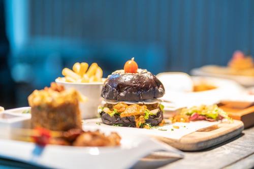 a sandwich on a plate on a table with french fries at VOUK Hotel and Suites Nusa Dua Bali in Nusa Dua