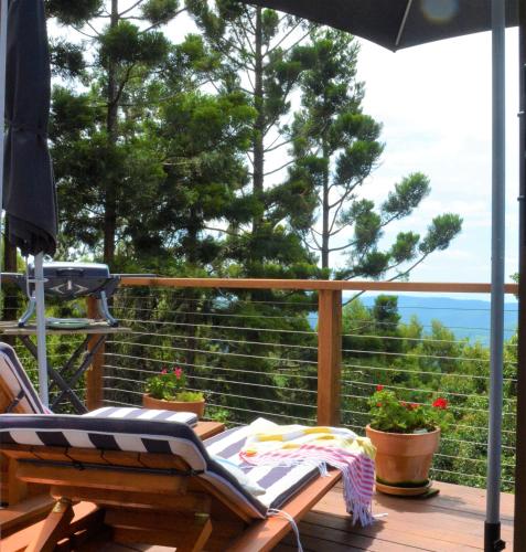 a deck with a chair and an umbrella and some plants at Willow Cabin in Beechmont