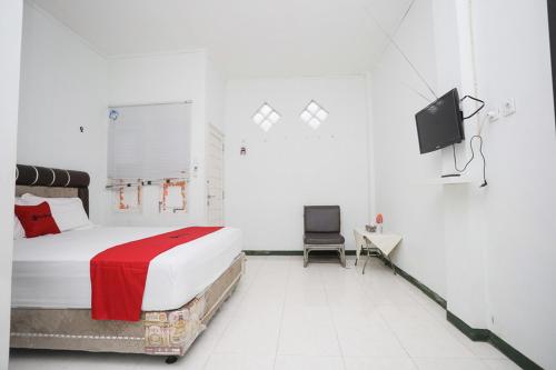パランカラヤにあるRedDoorz near Bundaran Kecil Palangkarayaのベッドルーム(ベッド1台、テレビ、椅子付)