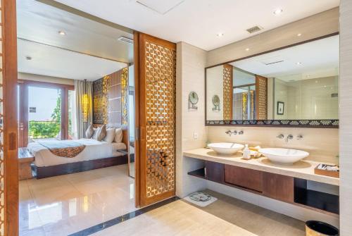 a bathroom with two sinks and a bed in the background at VOUK Hotel and Suites Nusa Dua Bali in Nusa Dua