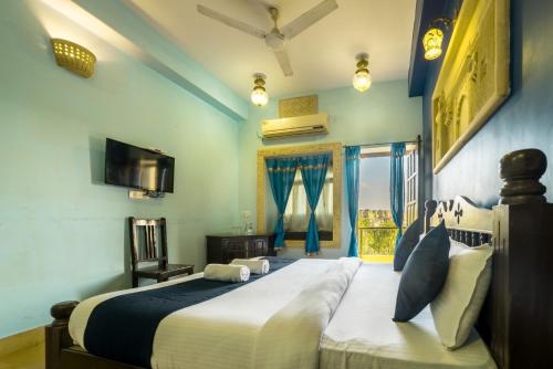 a bedroom with a large bed and a tv at Tripli Hotels Prithvi Palace in Jaisalmer