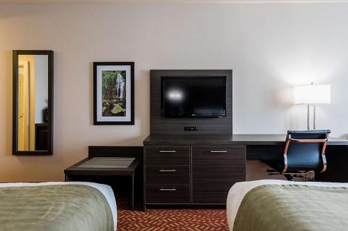 a hotel room with two beds and a desk with a television at Best Western Inn On The Bay in Owen Sound