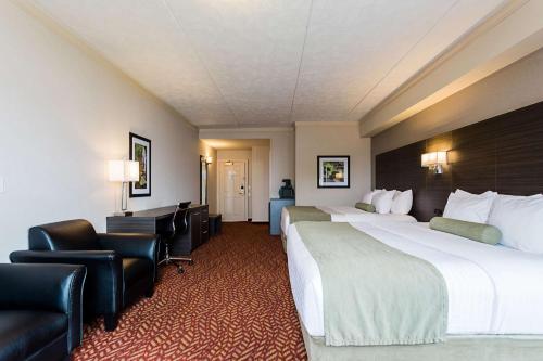 a hotel room with two beds and a desk and chairs at Best Western Inn On The Bay in Owen Sound