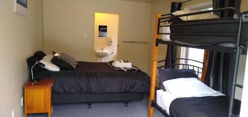a bedroom with two bunk beds and a bathroom at Tombstone Motel, Lodge & Backpackers in Picton
