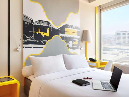 a hotel room with a bed with a laptop on it at KIMAYA Braga Bandung by HARRIS in Bandung