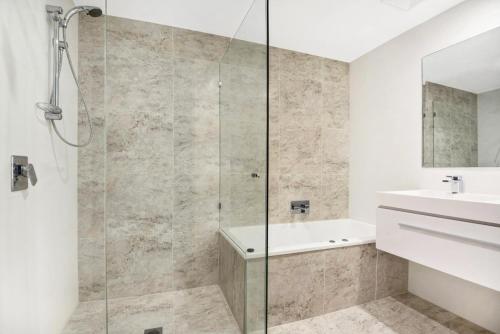 uma casa de banho com um chuveiro e um lavatório. em Beachfront Cabarita Apartment by Kingscliff Accommodation em Cabarita Beach