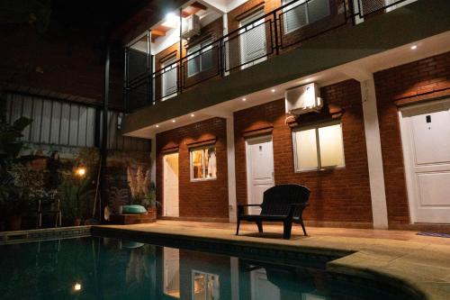 a chair sitting next to a swimming pool at night at Managua Apart Hotel in Puerto Iguazú