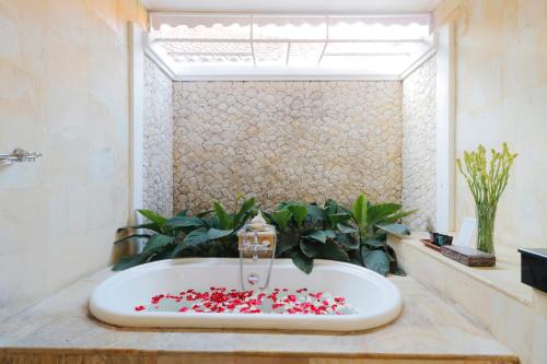 a bathroom with a bath tub filled with red hearts at Heliconia Villa in Seminyak