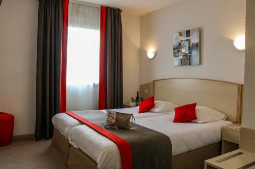 a hotel room with two beds and a window at Hôtel Le Kolibri in Tournus