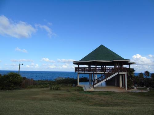 a gazebo with a green roof next to the ocean at Fosters West Bay Resort in West Bay