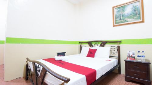 a bedroom with a bed with a red and white blanket at RedDoorz at Praferosa Resort Hotel Calamba in Calamba