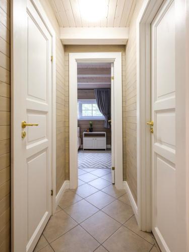 Un pasillo con puertas blancas y suelo de baldosas. en 5 stories, en Inkartai