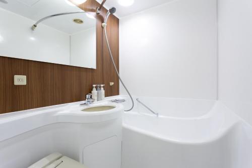 a white bathroom with a sink and a mirror at Shibuya Tokyu REI Hotel in Tokyo