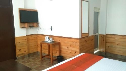 a bedroom with a bed and a tv and a table at Highland Village Resort in Dharmsala