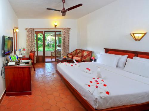 um quarto com uma cama grande e uma televisão em Abad Harmonia Ayurvedic Beach Resort em Kovalam