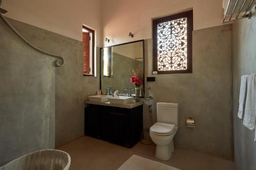 a bathroom with a toilet and a sink and a window at Villa Sunbird in Negombo