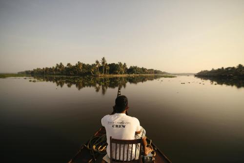 a man sitting in a boat on the water at Spice Coast Cruises - Houseboat, A CGH Earth Experience in Alleppey