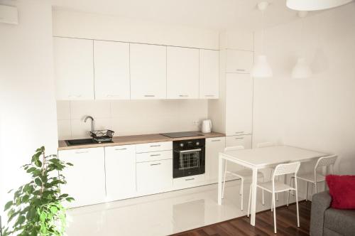 a kitchen with white cabinets and a white table at Apartament Rosso in Łódź