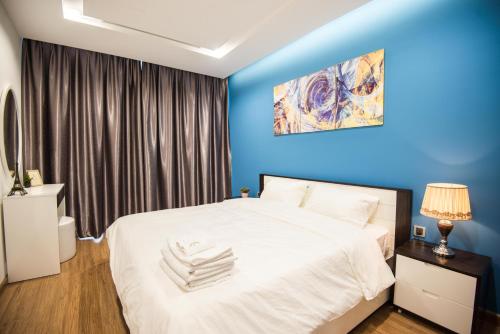 a bedroom with a large white bed and blue walls at Vinhomes Metropolis luxury Hotel & Residence in Hanoi