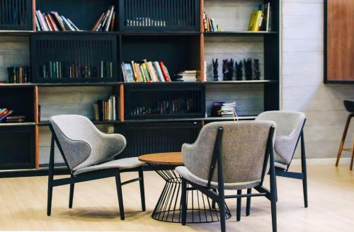 two chairs and a table in front of a book shelf at 2 Bedroom 2 BATHROOM NEAR SUMWAY PYRAMID in Subang Jaya
