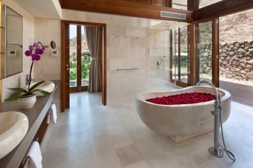a bathroom with a tub filled with red flowers at Herbert Samuel Royal Shangri-La Eilat in Eilat