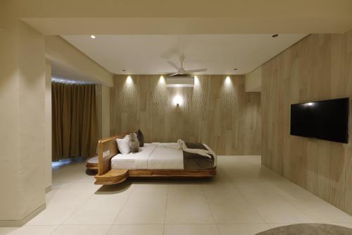 a bedroom with a bed and a flat screen tv at Artilla Inn in Ahmedabad