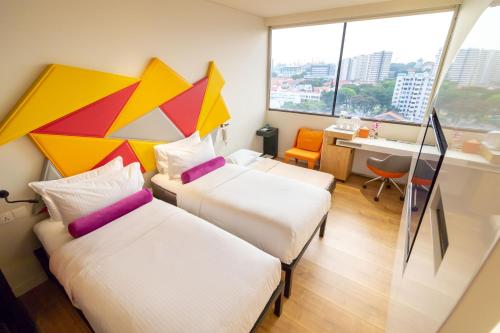 a hotel room with two beds and a desk at Ibis Styles Singapore On Macpherson in Singapore