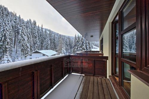 a balcony with a view of a snow covered forest at St. Peter Apartment in Špindlerův Mlýn