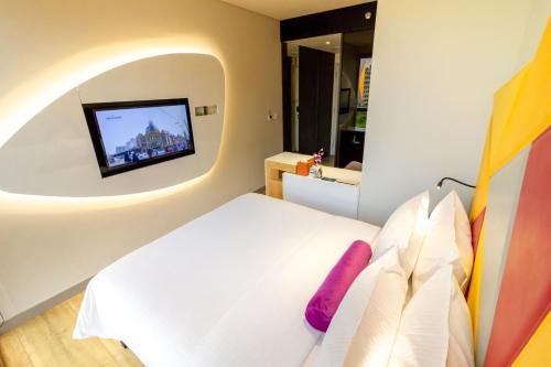 a bedroom with a bed and a tv on a wall at Ibis Styles Singapore On Macpherson in Singapore