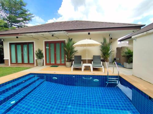 einen Pool mit zwei Stühlen und einem Sonnenschirm neben einem Haus in der Unterkunft Aonang Private Villa - Private Pool & Garden in Ao Nang Beach