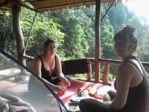 two women sitting on a table on a porch at LOVELY JUNGLE LODGE & JUNGLE TREKING only book with us in Bukit Lawang