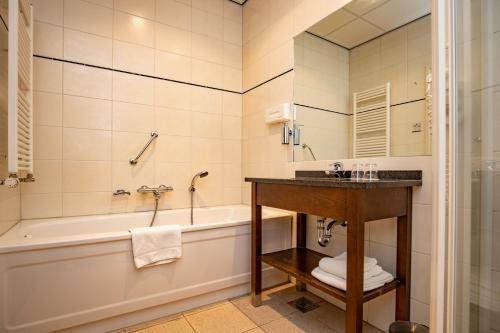 a bathroom with a tub and a sink at Fletcher Hotel Restaurant Amersfoort in Amersfoort