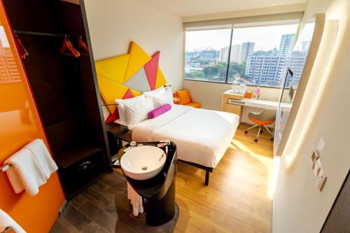 a hotel room with a bed and a desk and a window at Ibis Styles Singapore On Macpherson in Singapore