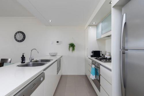 a white kitchen with a sink and a refrigerator at SK2 - CHARMING Skyline CBD w River Views 3 BR Private Apartment in Brisbane