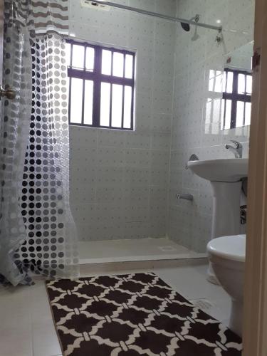 a bathroom with a black and white shower and a sink at Madison guest house in Nanyuki