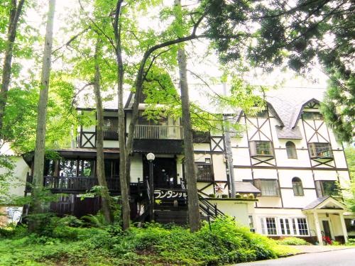 a large white house with a porch and trees at Rantanrirun ランタンリルン in Hakuba
