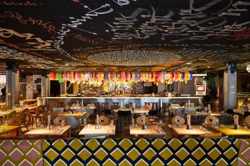 a restaurant with tables and chairs and a bar at Mama Shelter Bordeaux Centre in Bordeaux