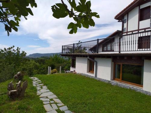 a house with a balcony and a grass yard at Casa Rural Olazi in Oiartzun