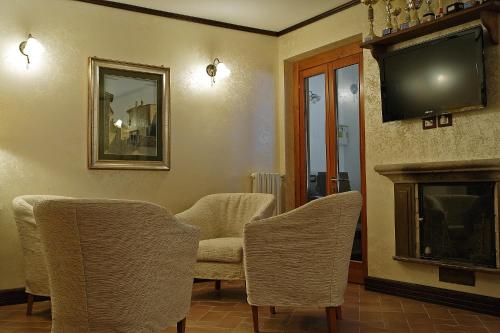 a living room with chairs and a tv and a fireplace at B&B IL PINO in Pescocostanzo