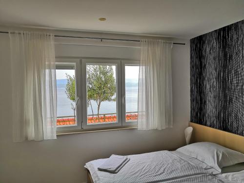 sypialnia z łóżkiem i oknem z widokiem w obiekcie Apartments Nostro w Omišu