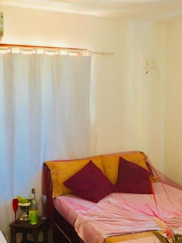 a bedroom with a bed with a curtain and a table at Casas Coloniais in Morro de São Paulo