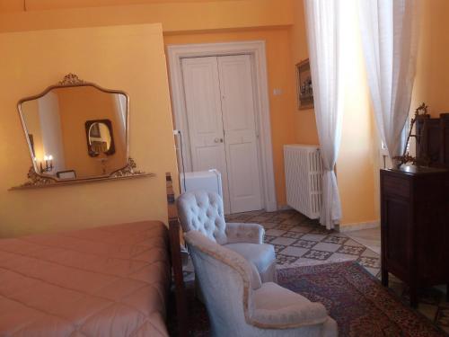 a bedroom with a bed and two chairs and a mirror at Antico Palazzo Spinola in Gallipoli