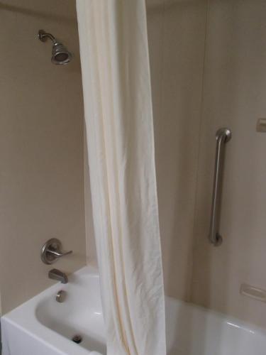 a bathroom with a shower with a white shower curtain at Wingate by Wyndham Bossier City in Bossier City