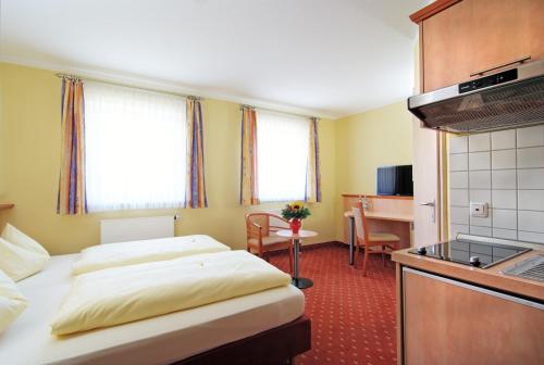 エルディングにあるMikro Apartments Erdingのベッド2台とキッチンが備わるホテルルームです。