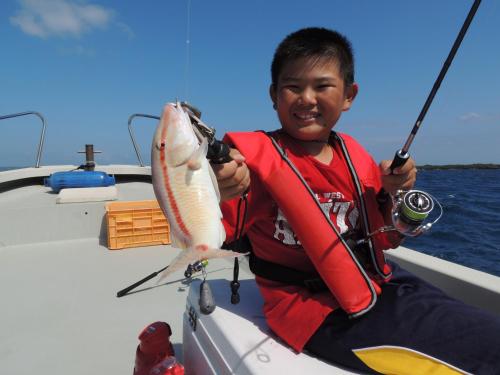 młody chłopiec trzymający rybę na łodzi w obiekcie Umi no Yado Umikaze w mieście Henza