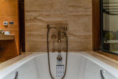 a bath tub with a faucet in a bathroom at Phor Liang Meun Terracotta Arts in Chiang Mai