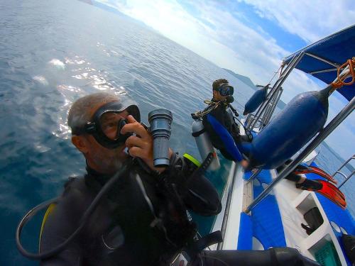a man on a boat in the water with a camera at Chindonan Dive and Beach Resort in Coron