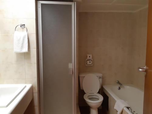 a bathroom with a toilet and a tub and a sink at Safari Hotel & Convention Centre in Rustenburg